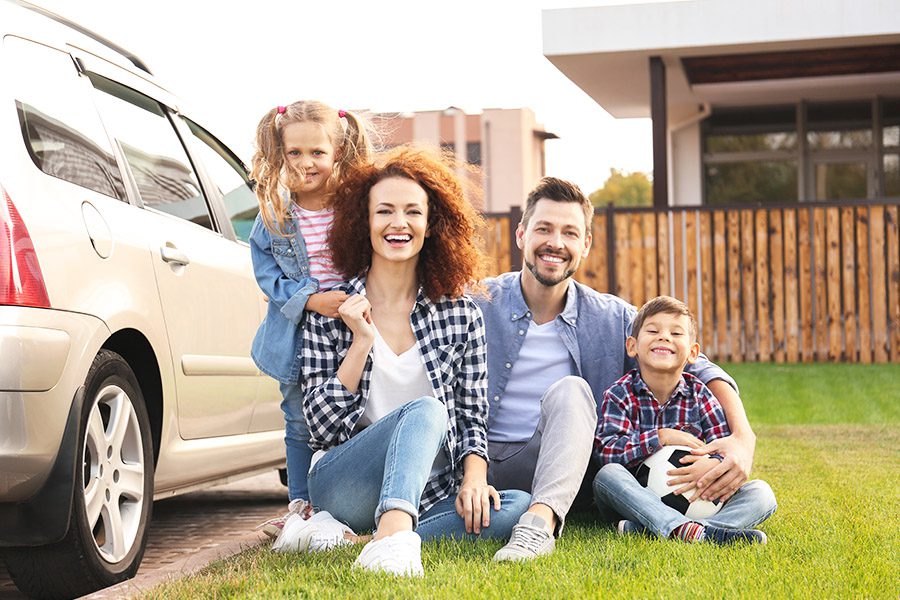 Personal Insurance - Young Family Portrait With Children Near Their Car in the Front Yard on Family Home on a Summer Day