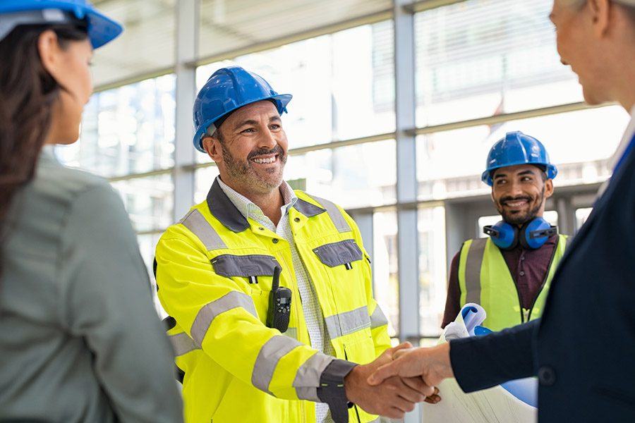 Specialized Business Insurance - Smiling Architect and Contractor Shaking Hands at Construction Site